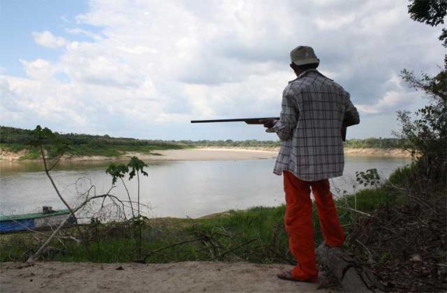 Persona armata di fucile lungo il fiume Volontario fiume Jurua Amazzonia